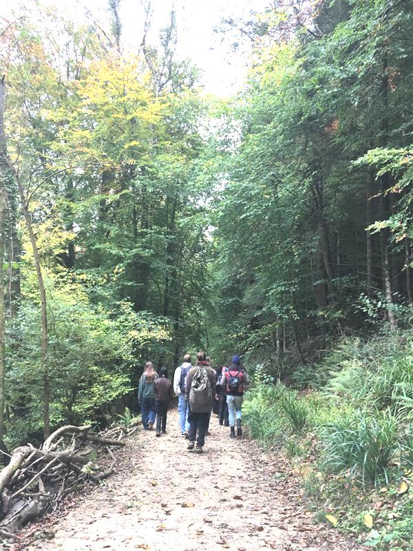 Some figures walking down down a steep hill in the countryside
